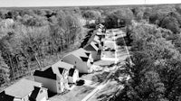 a black and white photo of a row of houses in a wooded area